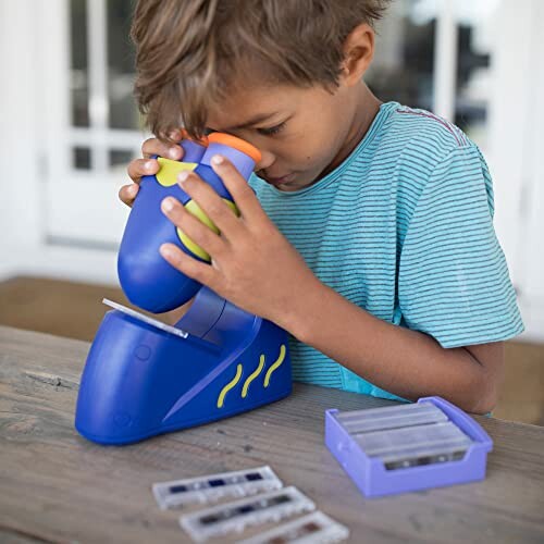 Child looking through a toy microscope on a table.