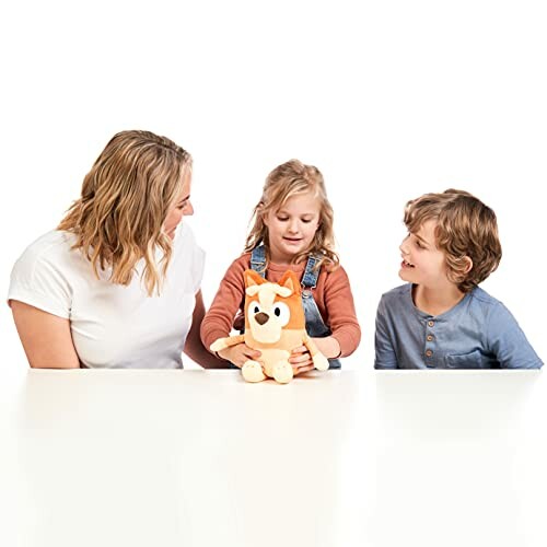 Two children and an adult playing with a plush toy at a table.