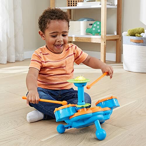 Toddler joyfully playing with toy drum set on the floor.