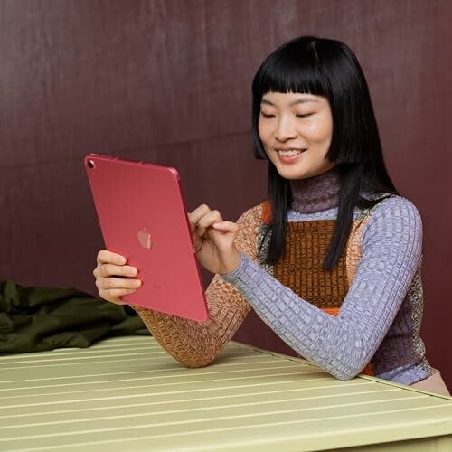 Woman smiling while using a red tablet